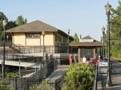 A wheelchair ramp through green hedges to the Oregon City Station.