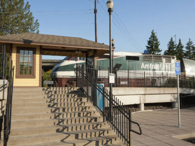 A train with the Amtrak logo on the side at Oregon City Station.