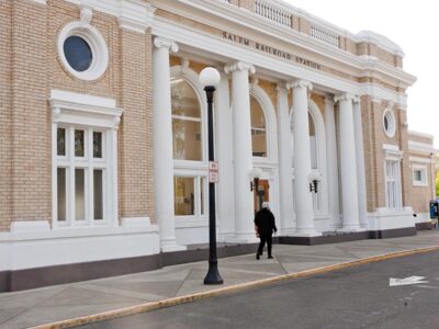 A person approaching the arched entrance to Salem Station. The person seems small relative to the arches.