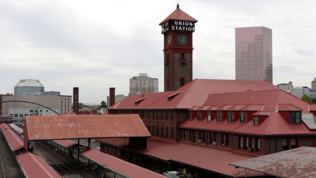 A view of the red roof tops with a brick clock tower in the background with large white letters spelling "Union Station".