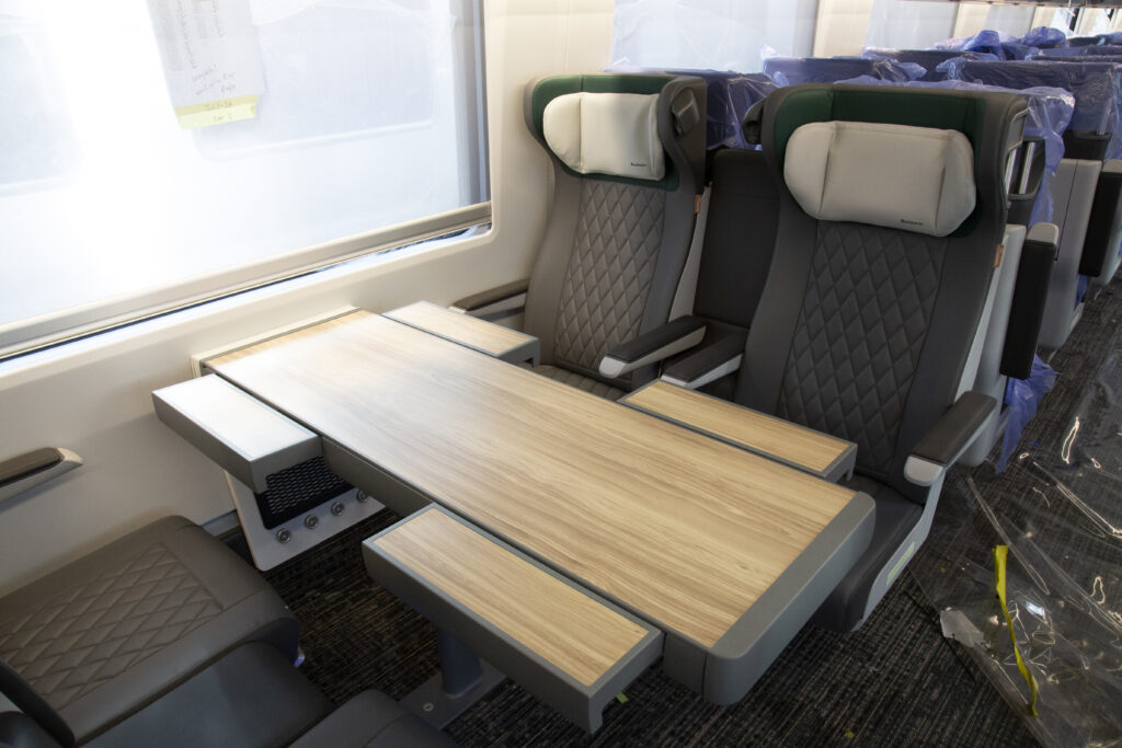 Seats in the interior of the train. There is a table between a set of 4 sets, with small extensions to the table available for each seat.