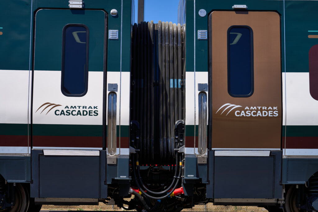 Photo of a new Amtrak Cascades Coach Car door on the left and a new Amtrak Cascades Business Car gold door on the right.